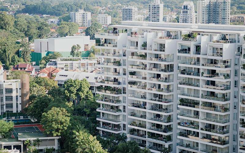 High-rise condominium buildings with glass balconies surrounded by greenery and cityscape views
