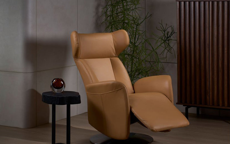 tan leather recliner chair with footrest extended, placed beside a small black side table in a modern living room setting