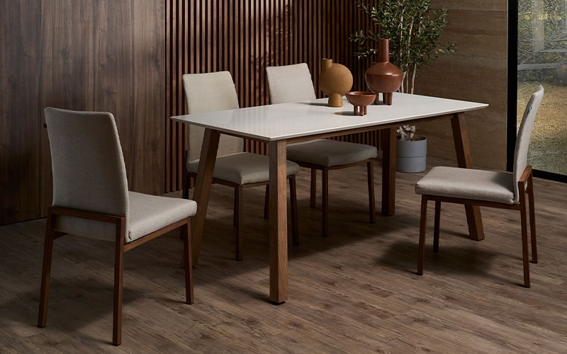 modern dining room setup with a white rectangular table, four beige cushioned chairs with wooden legs